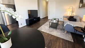 Een moderne woonkamer met een flatscreen televisie, een bank, een salontafel en een eettafel.