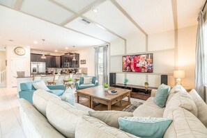 A modern living room with a sofa set, a coffee table, and a TV. - 8BR Resort Home: Private Theater, Game Room, Heated Pool, Lazy River Near Disney (Four Corners)