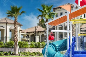 A water play area with a slide and a red bucket. - 8BR Resort Home: Private Theater, Game Room, Heated Pool, Lazy River Near Disney (Four Corners)