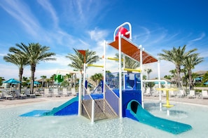 A water play area with slides and a pool, surrounded by palm trees and lounge chairs. - 8BR Resort Home: Private Theater, Game Room, Heated Pool, Lazy River Near Disney (Four Corners)