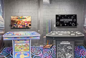 Habitació amb un joc de taula amb temàtica de Mario, un televisor que mostra un joc de Mario i una taula amb temàtica espacial i un joc.
