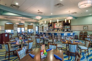 A hotel lobby with multiple dining tables and chairs, a bar area, and a reception desk. - 8BR Resort Home: Private Theater, Game Room, Heated Pool, Lazy River Near Disney (Four Corners)