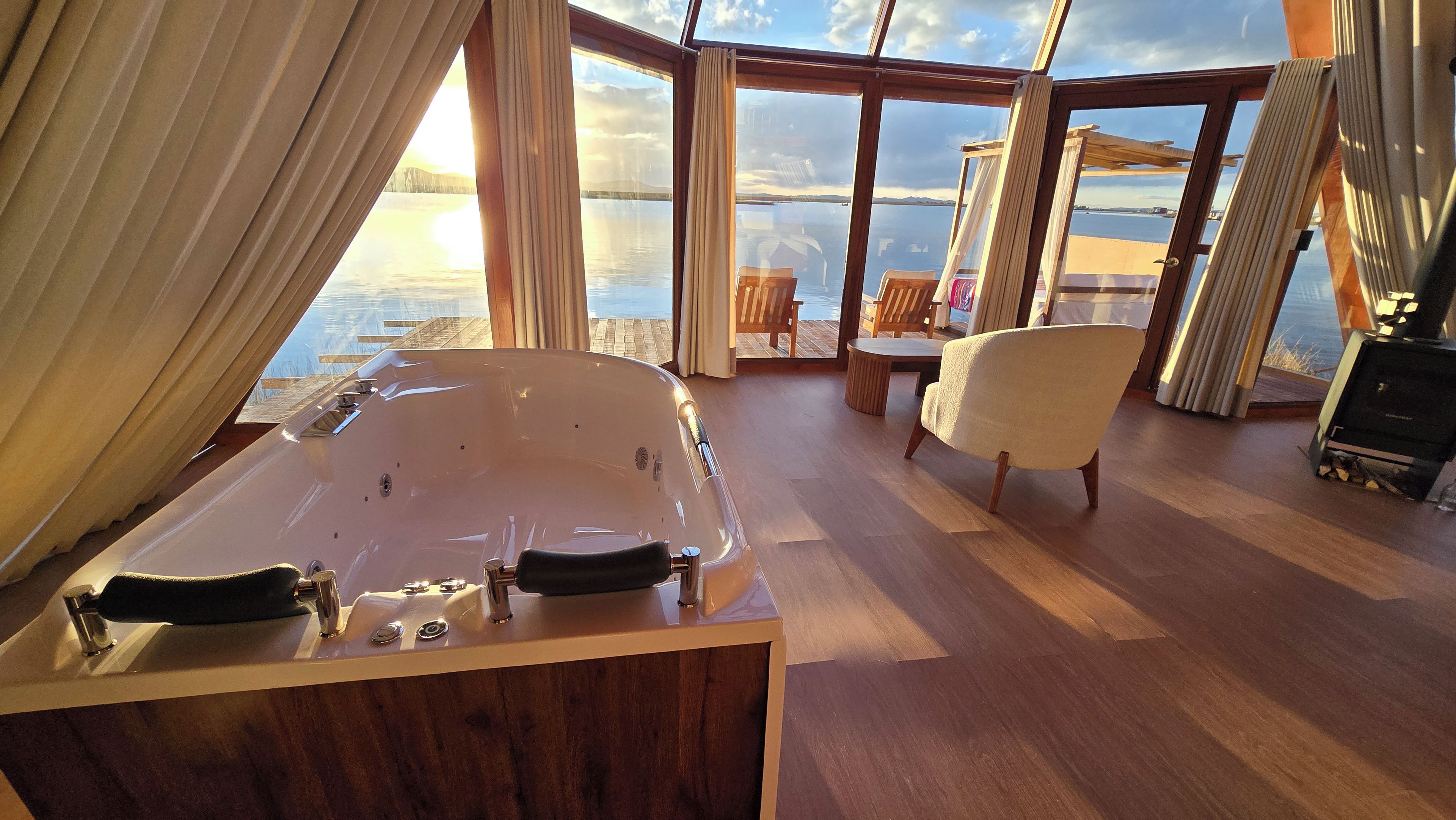 Une pièce avec une grande fenêtre, un plancher en bois, une baignoire et une chaise.