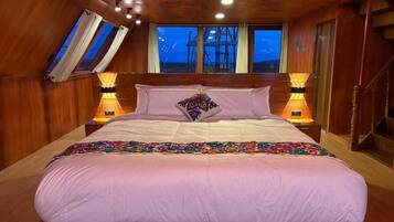 Une chambre avec un grand lit, des murs en bois, une lucarne et une vue sur l’extérieur.