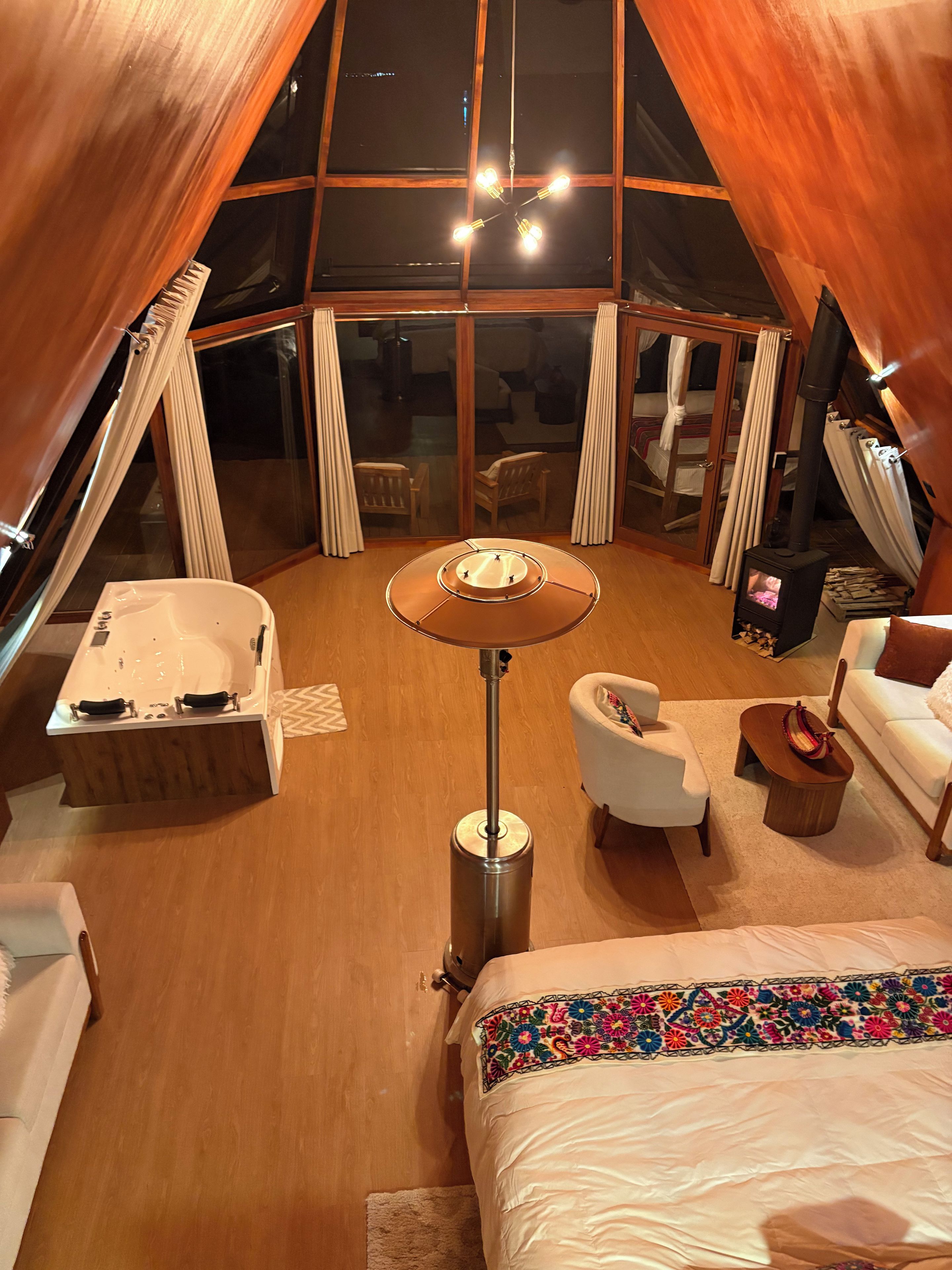 A tent-style room with a central table, a sofa, a chair, a small table, and a bathtub.