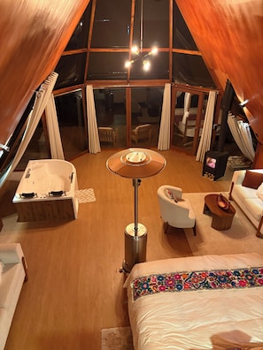 Habitación tipo tienda de campaña con una mesa central, un sofá, una silla, una mesita y una bañera.
