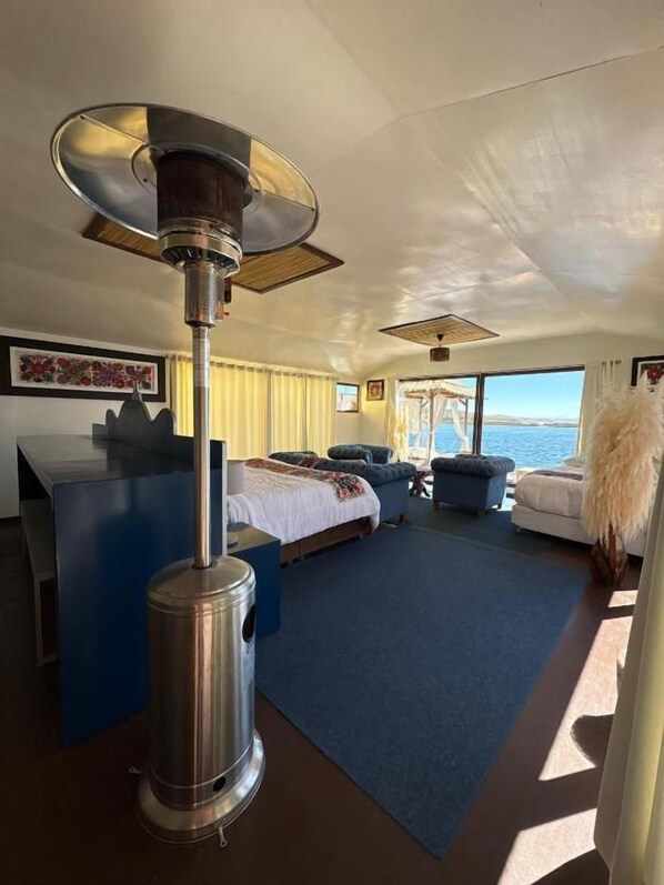 A room with a bed, a blue sofa, a heater, and a view of the sea.
