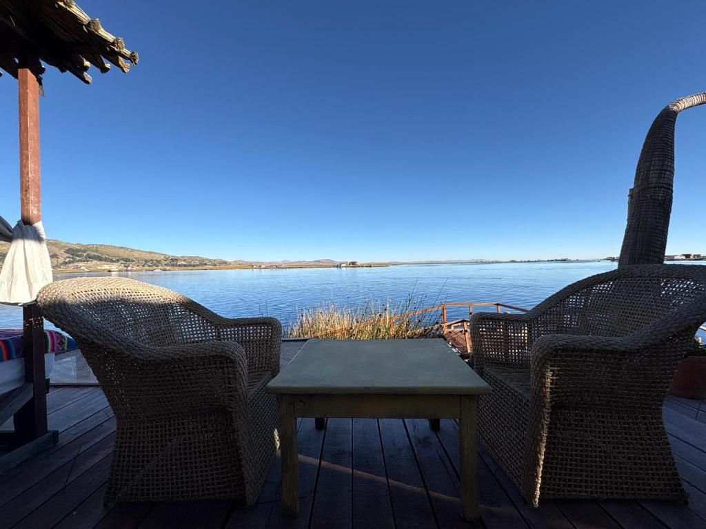 A deck with wicker furniture overlooking a calm body of water.