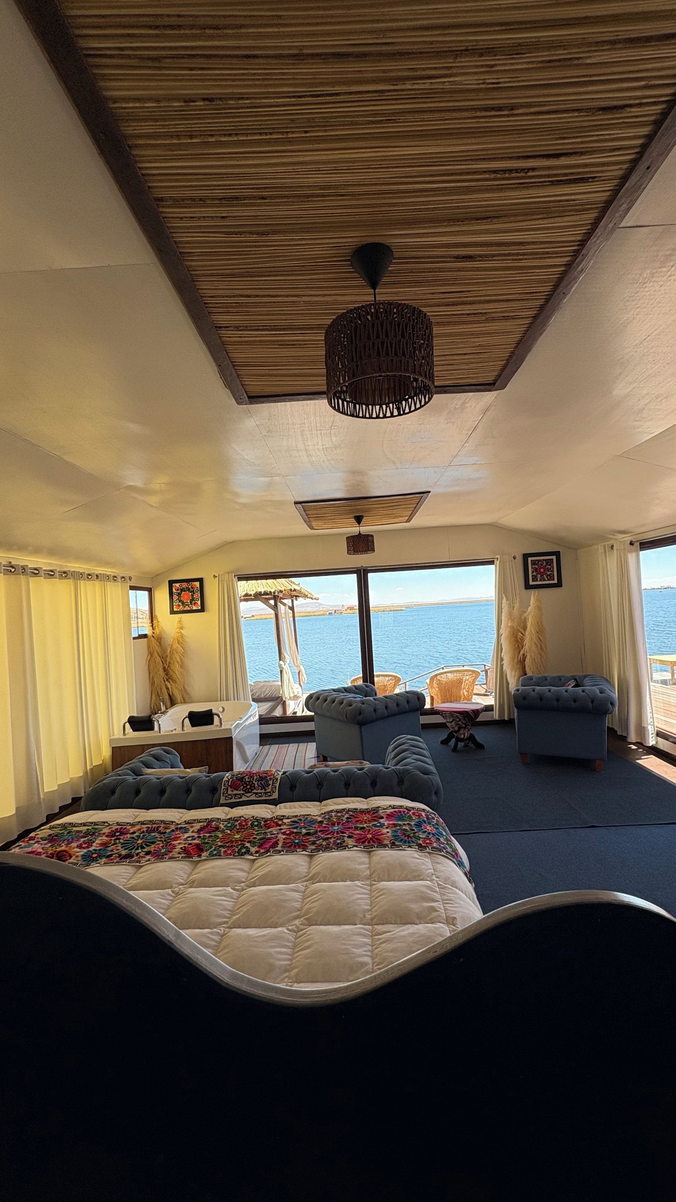A room with a bed, a sofa, and a view of the sea.
