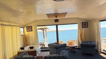 A room with a bed, a sofa, and a view of the sea.