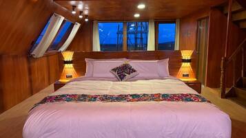 A bedroom with a large bed, two bedside lamps, a window, and a wooden ceiling.
