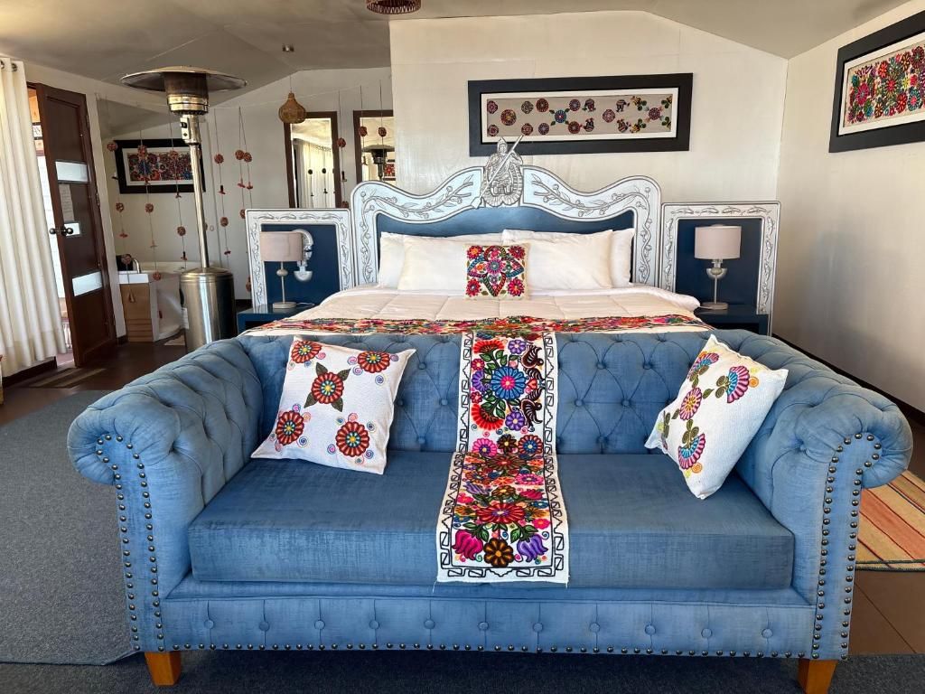 Une chambre à coucher avec un grand lit, un canapé bleu recouvert de tissu et un tapis décoratif.