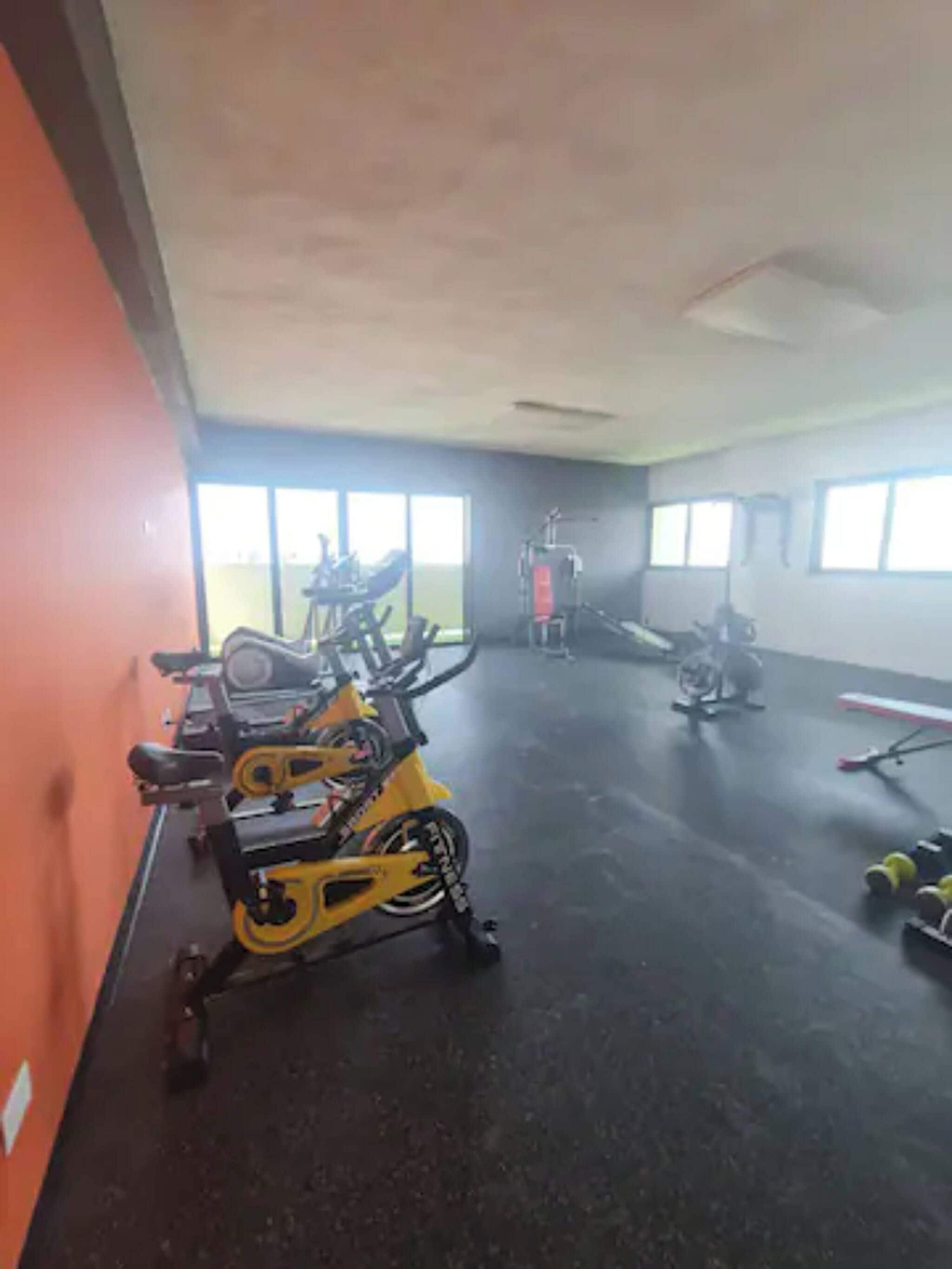 A gym with stationary bikes, a treadmill, and weights.