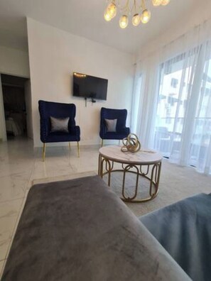 A modern living room with two sofas, a round coffee table, and a flat-screen TV mounted on the wall. - Stylish Metropolitan 2 Bedroom Apartment (Santo Domingo)