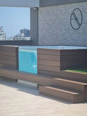 Eine Dachterrasse mit Pool, Holzdeck und einem Rauchverbot-Schild.