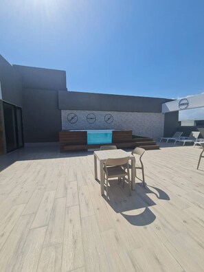 An outdoor seating area with a table and chairs, a pool table, and lounge chairs. - Stylish Metropolitan 2 Bedroom Apartment (Santo Domingo)