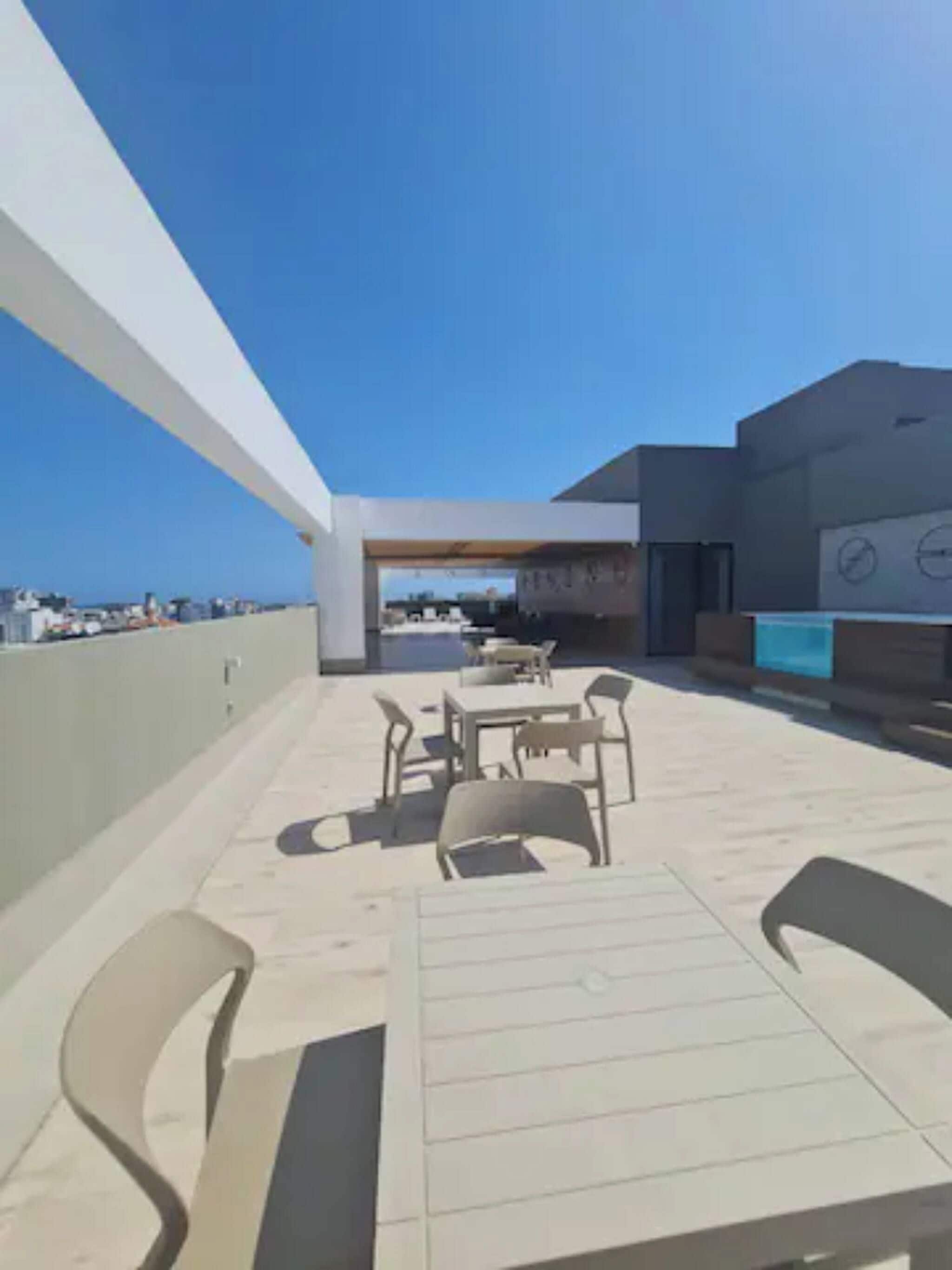Un patio al aire libre con mesa y sillas, vista al mar y un edificio de diseño moderno.