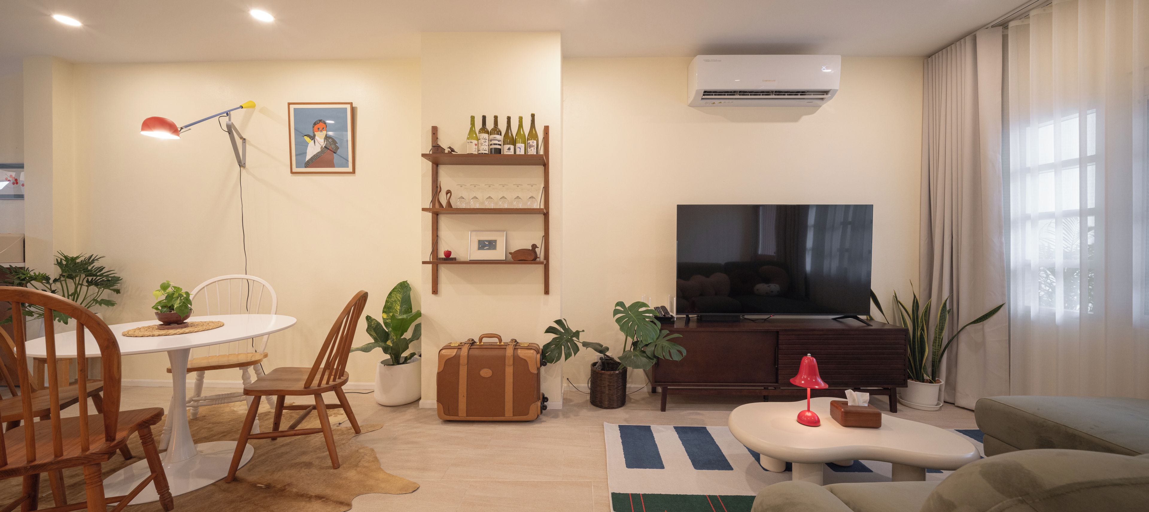 A living room with a television, a dining table with chairs, a sofa, and a coffee table.