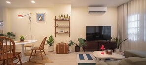 A living room with a television, a dining table with chairs, a sofa, and a coffee table. - Private2BR Townhome in the Heart of Nimman  Perfect for Families &Groups+parking (Chang Wat Chiang Mai)
