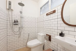 A bathroom with white subway tiles, a white toilet, a shower with a handheld showerhead, a handheld showerhead, a towel rack, and a mirror with a wooden frame. - Private2BR Townhome in the Heart of Nimman  Perfect for Families &Groups+parking (Chang Wat Chiang Mai)