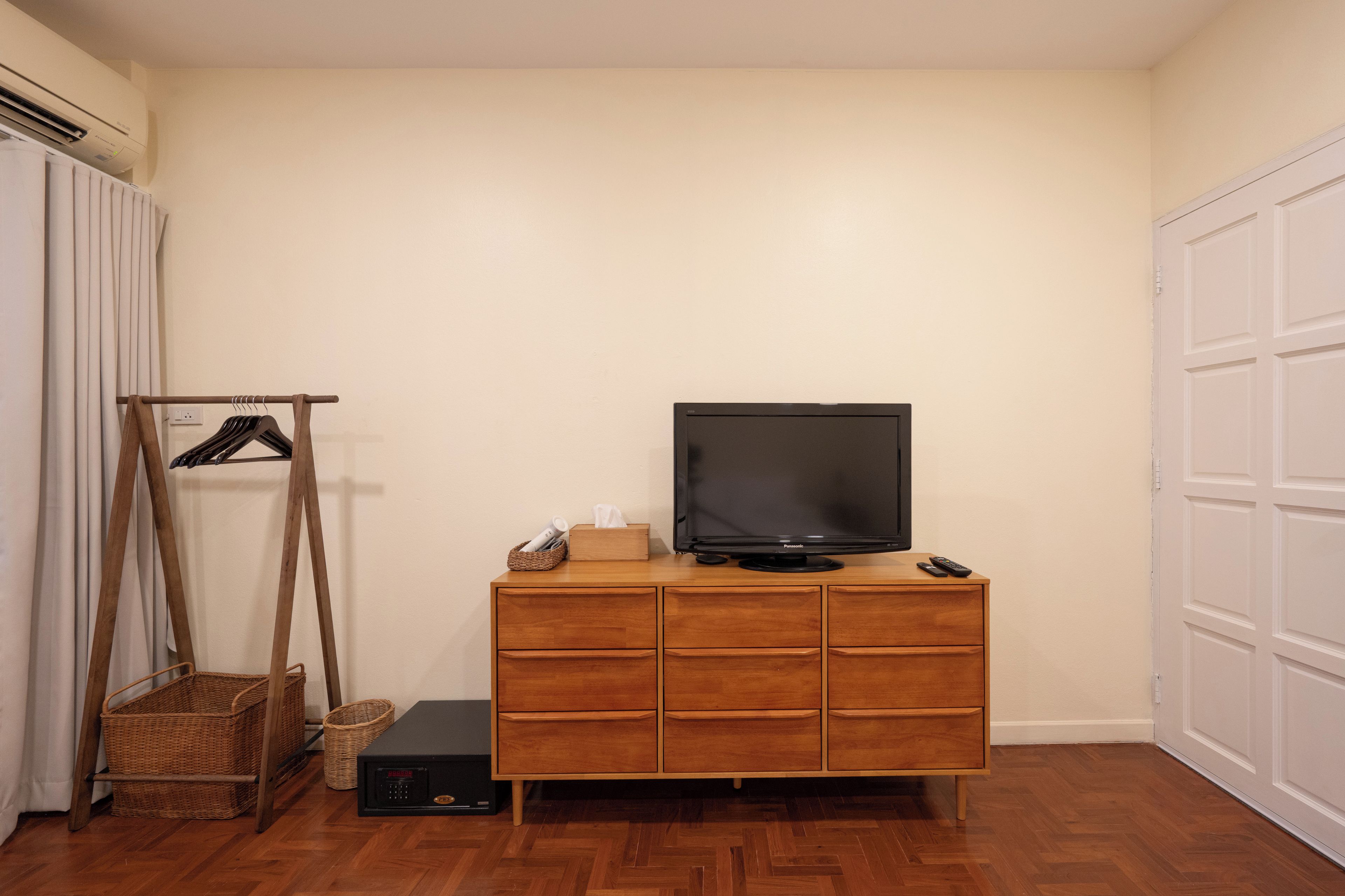 Ein Zimmer mit einem Holzkabinett, einem Fernseher darauf, einer Fernbedienung und einer kleinen Schachtel auf dem Kabinett.