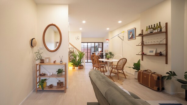 Una sala de estar moderna con un sofá, una mesa de comedor con sillas, un espejo y una estantería con botellas de vino.
