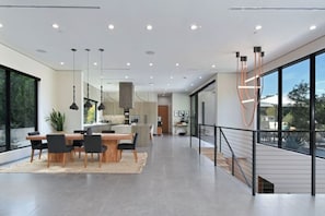 A modern interior with a dining area, kitchen, and large windows. - Round Valley Residence (Sherman Oaks)