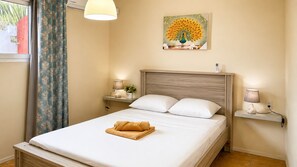 A hotel room with a bed, two bedside tables, a lamp, a painting, and a window with curtains.