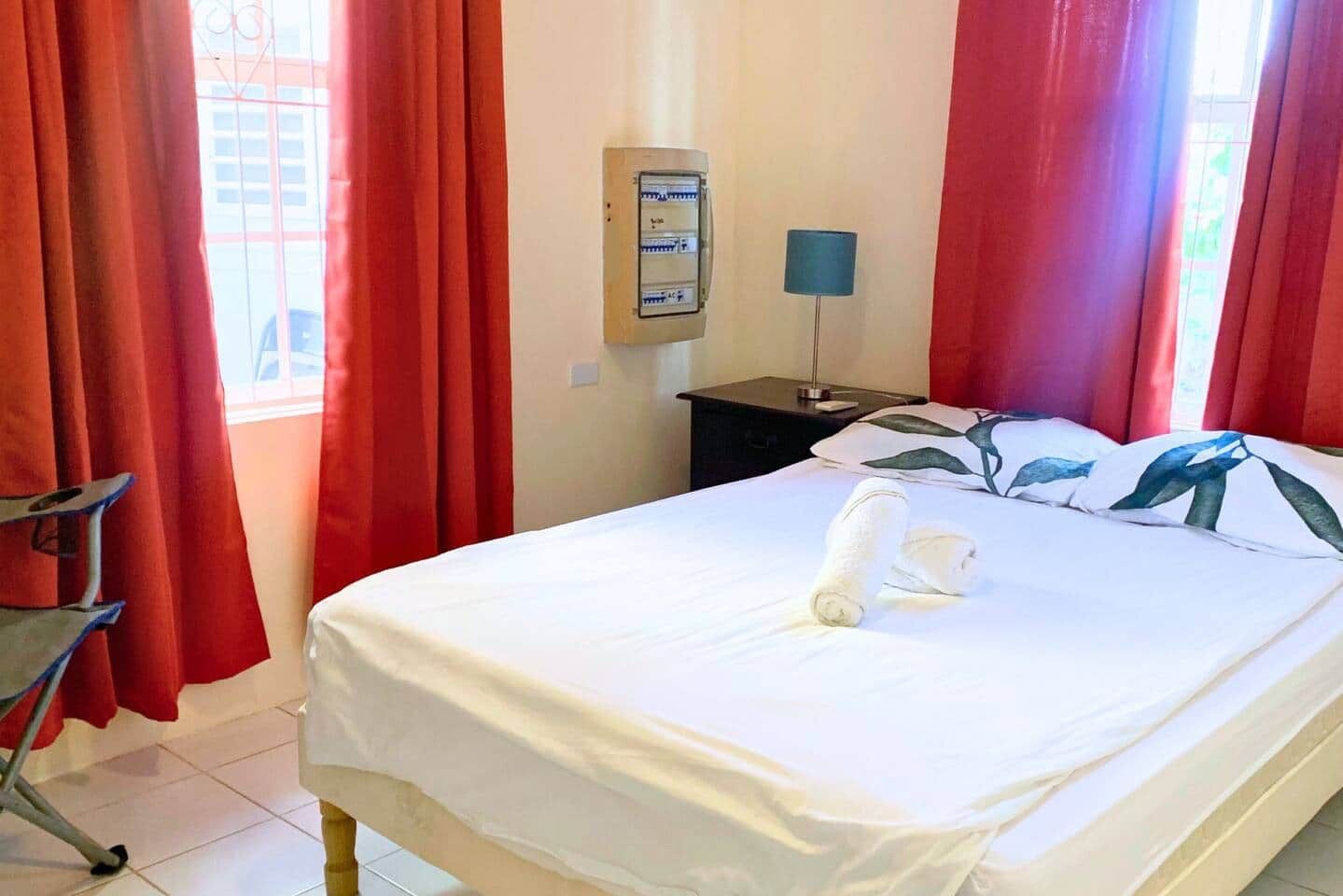 Ein Hotelzimmer mit einem Bett, einem Nachttisch, einer Lampe und einem Fenster mit Vorhängen.