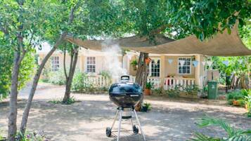 A barbecue grill outdoors with a house in the background.