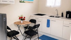 A compact kitchen with a sink, a coffee maker, and a small dining area with chairs and a table. - Apartment Near Beaches, Dining & Attractions (Willemstad)