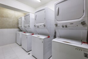 A row of white, modern, front-loading washing machines in a clean, tiled laundry room. - Girasol - Loft Condesa - 01B (Mexico City)