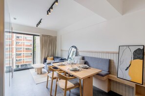 A modern hotel room with a dining area, a sofa, and a large window. - Girasol - Loft Condesa - 01B (Mexico City)