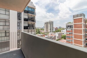 A balcony with a view of surrounding buildings, including a tall structure in the distance. - Girasol - Loft Condesa - 01B (Mexico City)