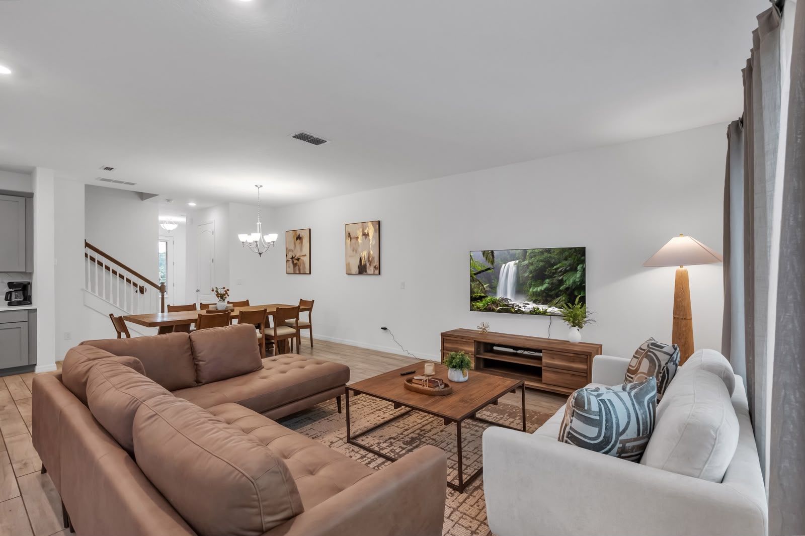 Ein modernes Wohnzimmer mit Sofa, Couchtisch, Fernseher und Essbereich.