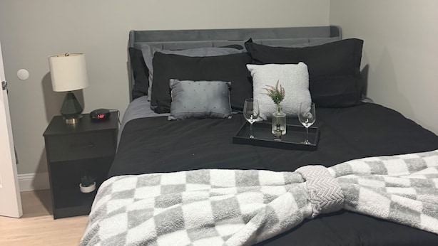 A bedroom with a bed, a nightstand, a lamp, and a wall decoration spelling 'HOME'.