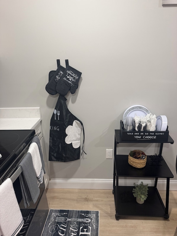 A kitchen area with a black oven, a microwave, and a black shelf with dishes and a basket.