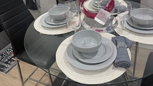 A dining table set with plates, bowls, and glasses, accompanied by a red decorative piece.