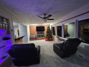 Un salon avec une cheminée, un sapin de Noël et un téléviseur fixé au mur.