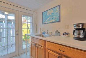 A kitchen with a large window, a coffee maker, and a framed map on the wall. - Charming Beach Cottage Steps from Village (Siesta Key)