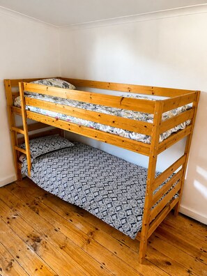 A bunk bed with a wooden frame and patterned bedding. - Family Farmhouse 3-Bed Retreat Near Sale (Sale)