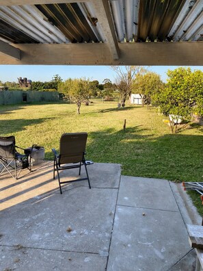 An outdoor patio area with a concrete floor, a folding chair, and a small table. - Family Farmhouse 3-Bed Retreat Near Sale (Sale)