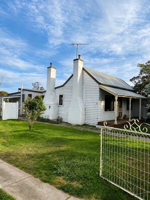 A white house with a chimney, a porch, and a fenced yard. - Family Farmhouse 3-Bed Retreat Near Sale (Sale)