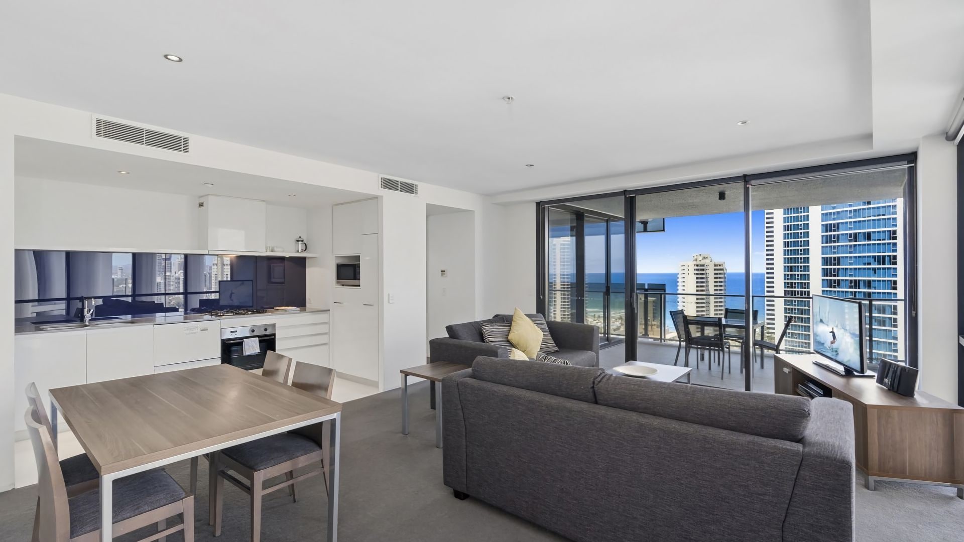 Un appartement moderne doté d’une cuisine, d’un coin repas et d’un balcon offrant une vue sur la ville.