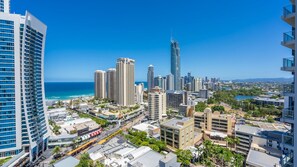 A cityscape with high-rise buildings, a clear blue sky, and a view of the ocean. - Circle On Cavil Apartment 2205 (Surfers Paradise)