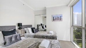 A hotel room with two beds, a large window, a painting, and a view of buildings. - Chevron Renaissance Apartment 1092 (Surfers Paradise)