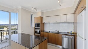A modern kitchen with a central island, stainless steel appliances, and a view of the city. - Chevron Renaissance Apartment 1135 (Surfers Paradise)
