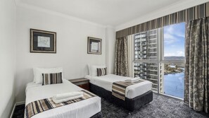 A hotel room with two beds, a large window with curtains, and artwork on the walls. - Chevron Renaissance Apartment 1224 (Surfers Paradise)