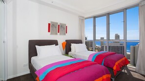 Ein Hotelzimmer mit zwei Betten, einem großen Fenster mit Blick auf die Stadt und einem Kunstwerk an der Wand.