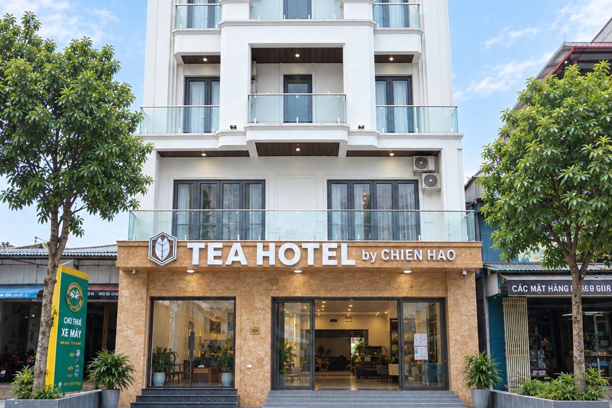 Un hotel de varios pisos con una fachada moderna, que cuenta con balcones en cada planta y una entrada a nivel de calle con un letrero que dice 'TEAHOTEL by CHIEN HAO'.